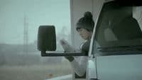 a woman reading a newspaper in front of a truck