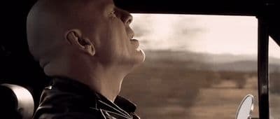 a bald man sitting in a car looking out the window