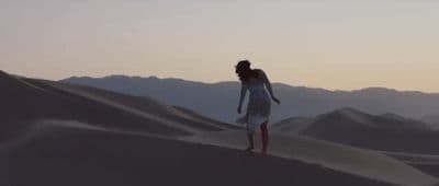 a woman standing on top of a sand dune