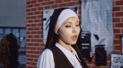a woman in a nun costume standing in front of a brick building