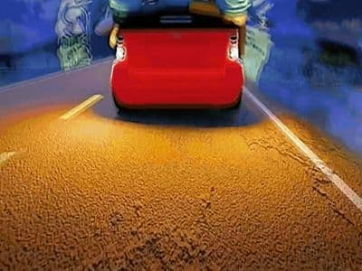 a person sitting on a suitcase in the middle of a road