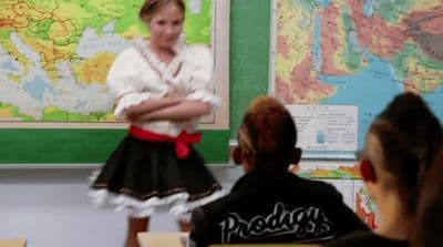 a girl in a black and white dress standing in front of a classroom