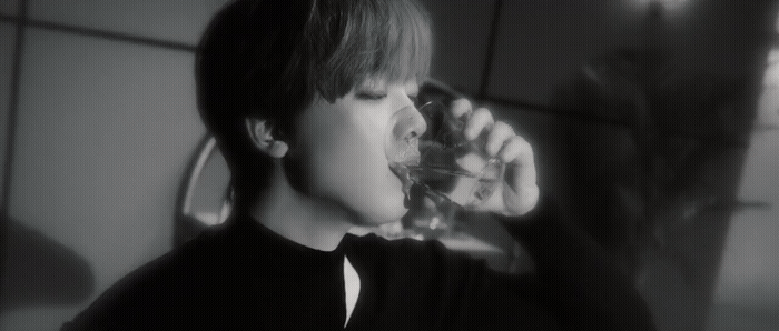 a young man drinking water from a glass