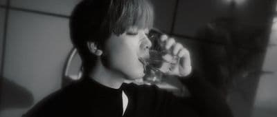 a young man drinking water from a glass
