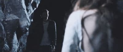 a man standing next to a woman in a cave
