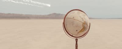 a mirror sitting on top of a metal pole in the middle of a desert