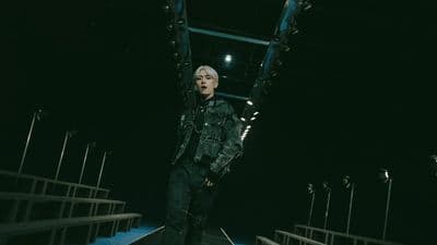 a man standing on a stage with his hands in the air