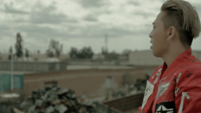 a man with a mohawk standing in front of a pile of garbage