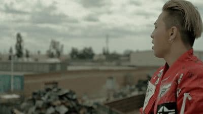 a man with a mohawk standing in front of a pile of garbage