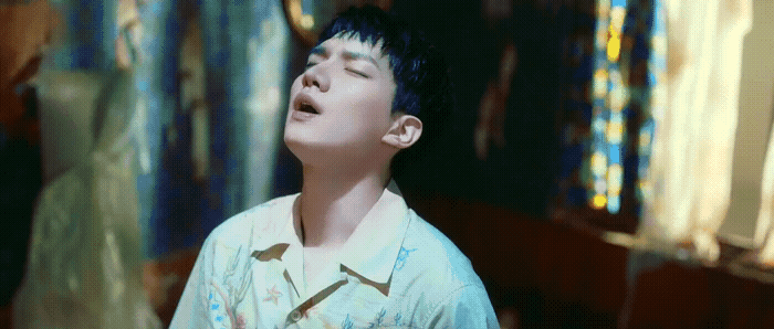 a young boy standing in front of a window with his eyes closed