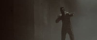 a man standing in a dark room with his arms outstretched