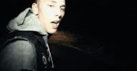 a man with a hoodie on standing in the dark