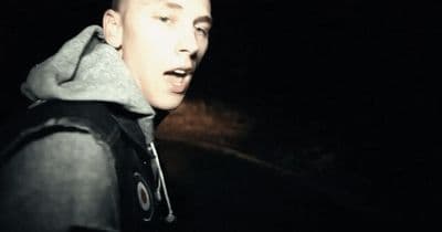 a man with a hoodie on standing in the dark