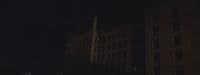 a dark city street at night with tall buildings