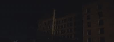a dark city street at night with tall buildings