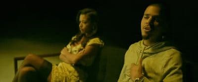 two people sitting on a couch in a dark room