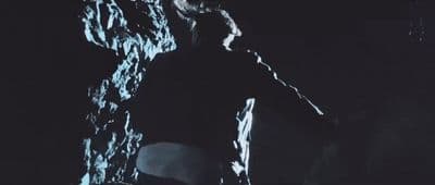 a man standing next to a large rock in the dark
