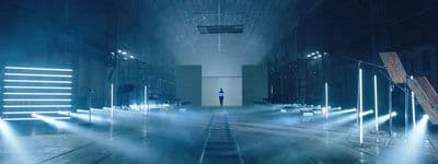 a person standing in a dark room with beams of light