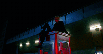 a man sitting on top of a red box in front of a building