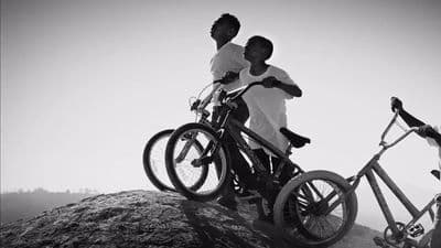a couple of men standing next to each other on top of a mountain