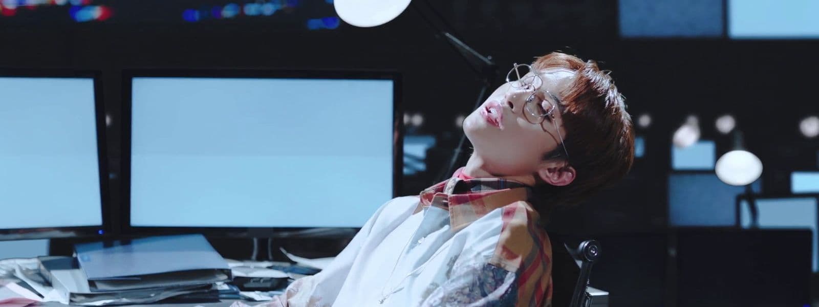 a person sitting at a desk with three monitors