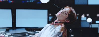 a person sitting at a desk with three monitors