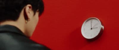 a man looking at a clock on a red wall
