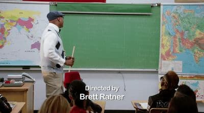 a man standing in front of a blackboard in a classroom