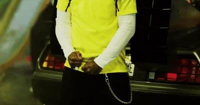 a man in a yellow shirt standing next to a car