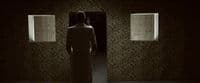 a person standing in a dark room with two windows