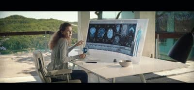 a woman sitting at a table in front of a computer screen