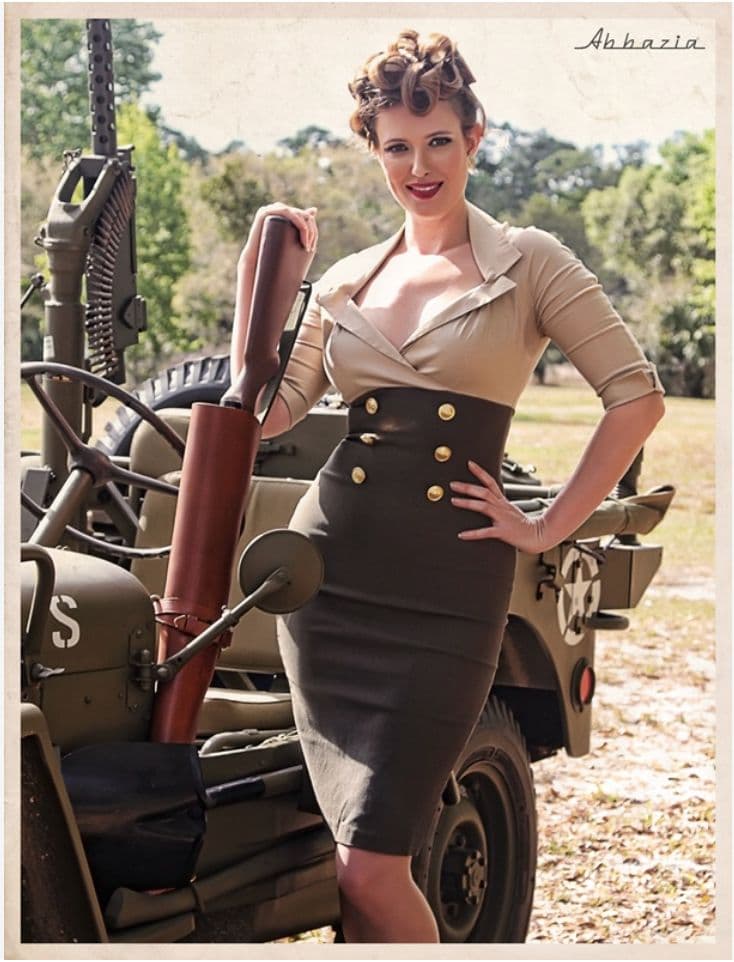 a woman in a dress standing next to an army vehicle