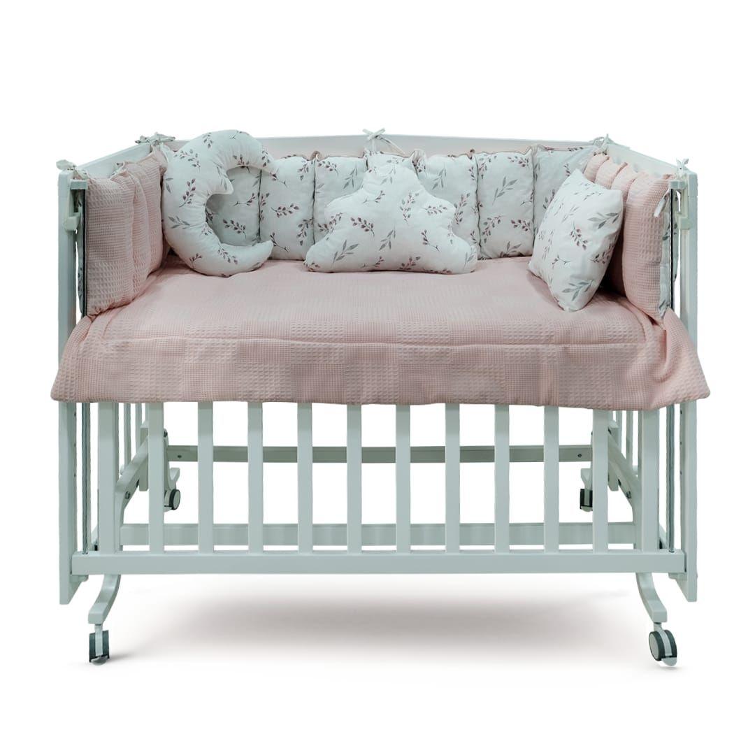 a baby crib with a pink and white cover