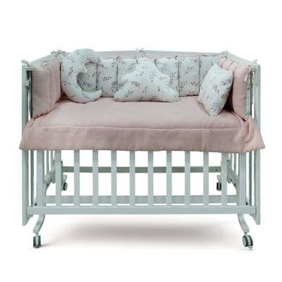 a baby crib with a pink and white cover