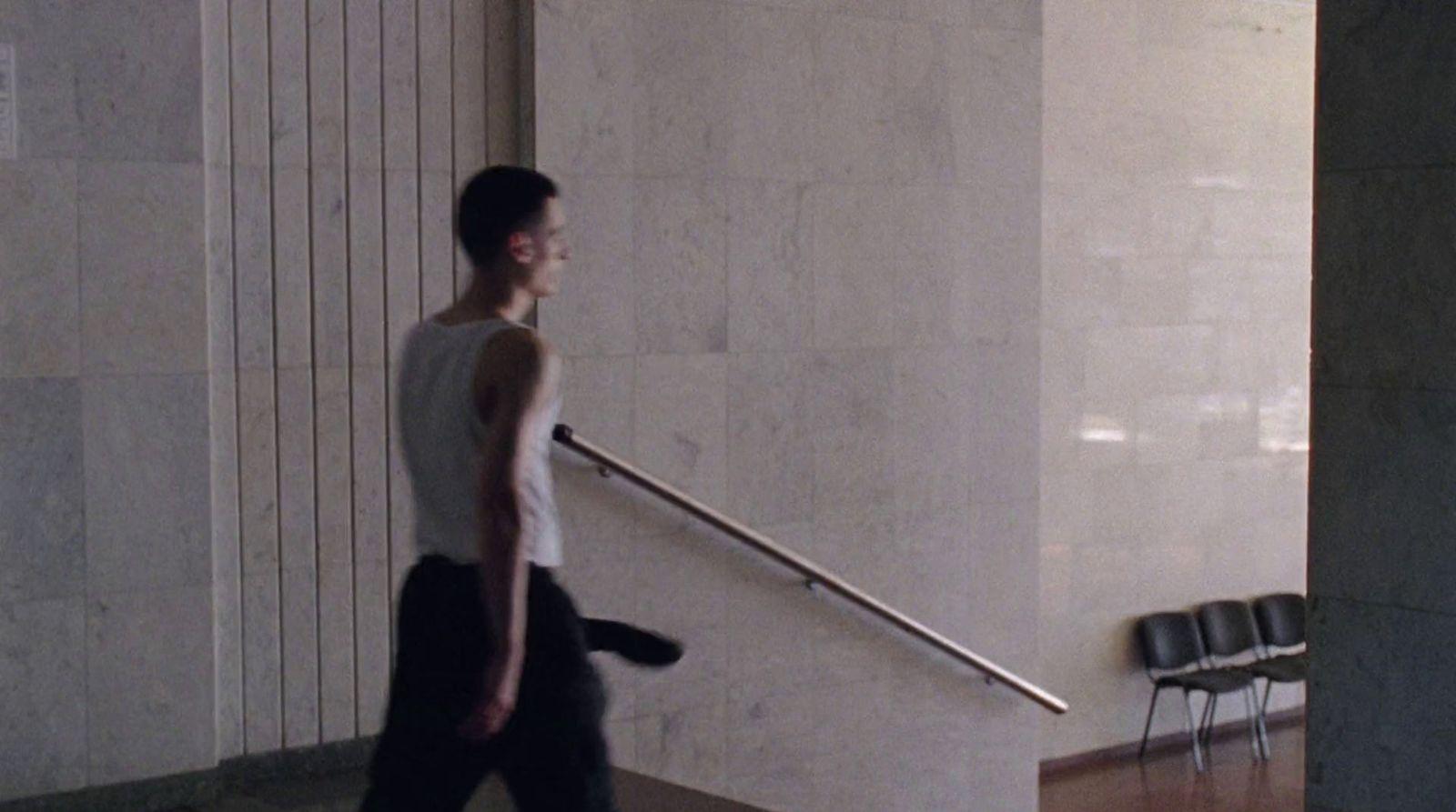 a man walking down a hallway carrying a suitcase