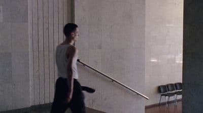 a man walking down a hallway carrying a suitcase
