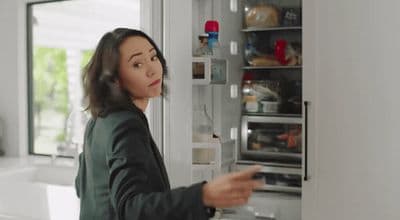 a woman standing in front of an open refrigerator