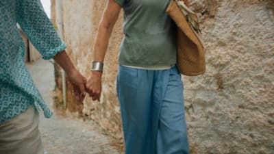 a couple of people walking down a street holding hands