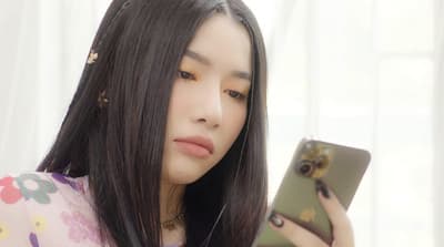 a woman with long black hair looking at her phone