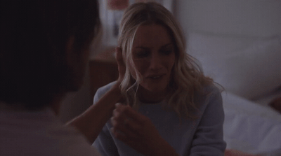 a woman is talking to a man in bed
