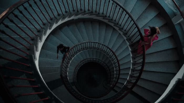 a woman is standing on a spiral staircase