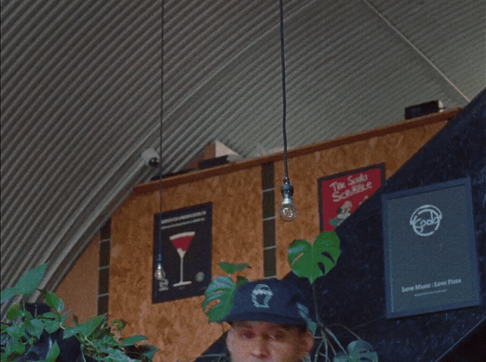 a man wearing a hat standing in front of a wall