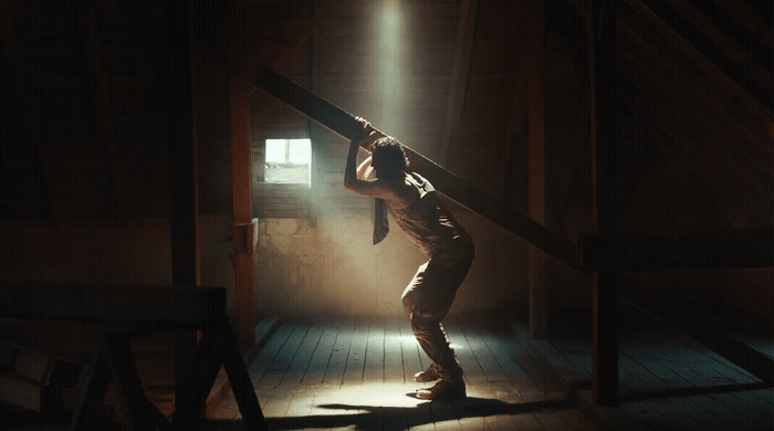 a man standing in a dark room holding onto a pole