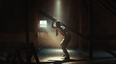 a man standing in a dark room holding onto a pole