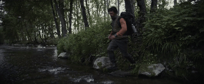 a man with a backpack walking across a river