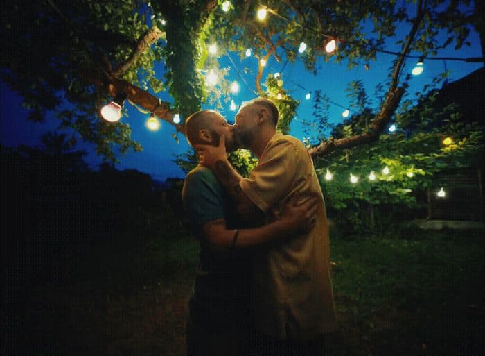 a couple of men standing next to each other under a tree
