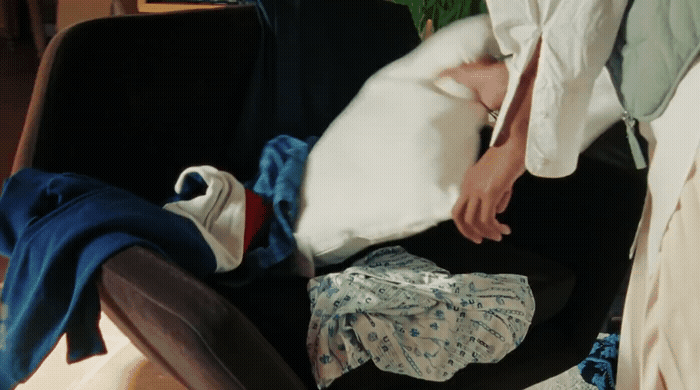 a person laying in a chair with a bunch of clothes on it