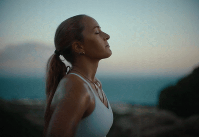 a woman in a white tank top looking at the sky