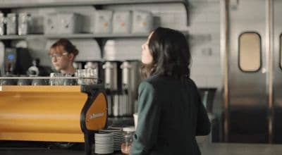 a woman standing in front of a coffee machine