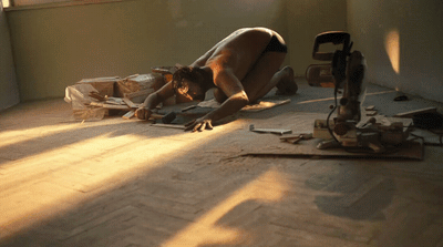 a man laying on the floor working on a piece of wood